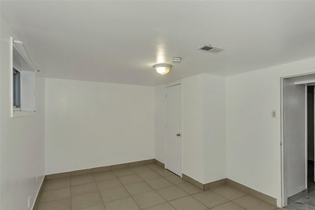 empty room with light tile patterned flooring, visible vents, and baseboards