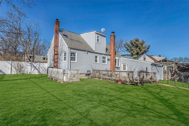 rear view of property featuring a lawn, a chimney, and fence