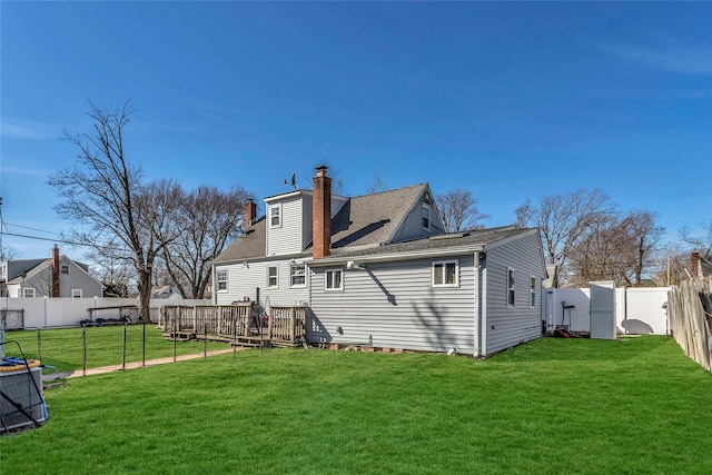 rear view of property with a yard, a fenced backyard, and a chimney