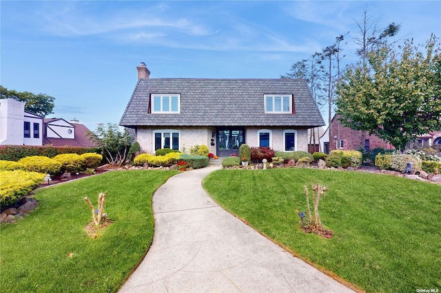 view of property featuring a front yard, brick siding, and a chimney