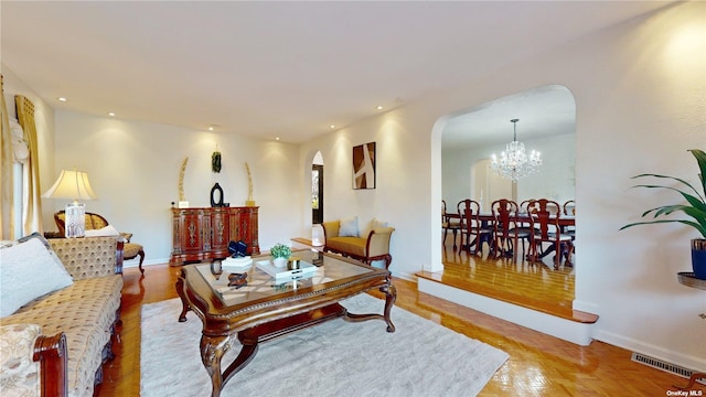 living area featuring arched walkways, visible vents, recessed lighting, and a chandelier