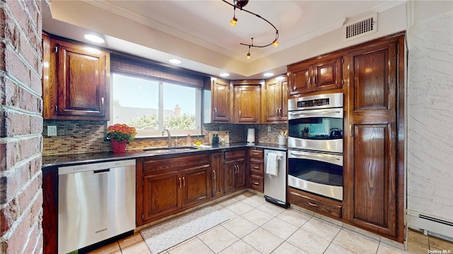 kitchen with dark countertops, ornamental molding, appliances with stainless steel finishes, and a sink