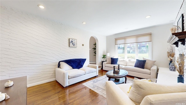 living room featuring recessed lighting, baseboards, arched walkways, and wood finished floors