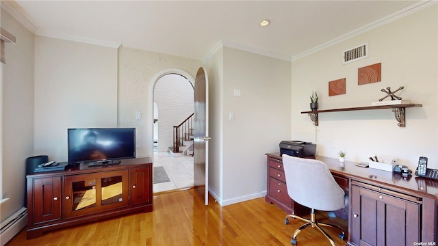 office with light wood finished floors, visible vents, a baseboard heating unit, ornamental molding, and arched walkways