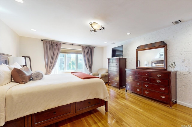 bedroom with recessed lighting, light wood-style floors, visible vents, and a textured wall