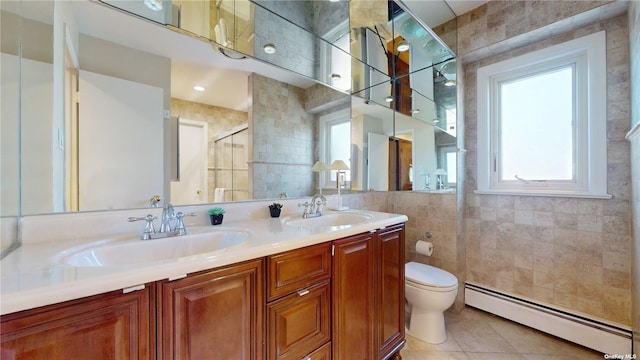 bathroom with a sink, a baseboard heating unit, tile walls, and tile patterned flooring