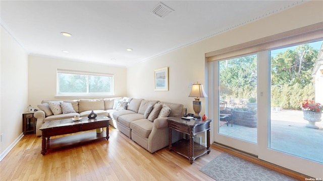 living room featuring visible vents, plenty of natural light, light wood-style floors, and ornamental molding