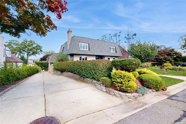 view of property exterior with mansard roof and a chimney