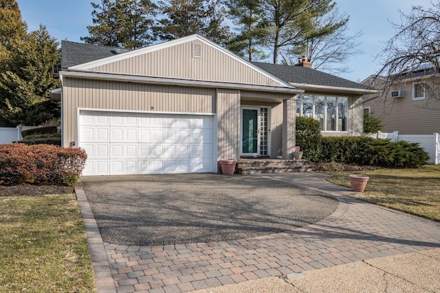 ranch-style house featuring fence, aphalt driveway, roof with shingles, a chimney, and a garage