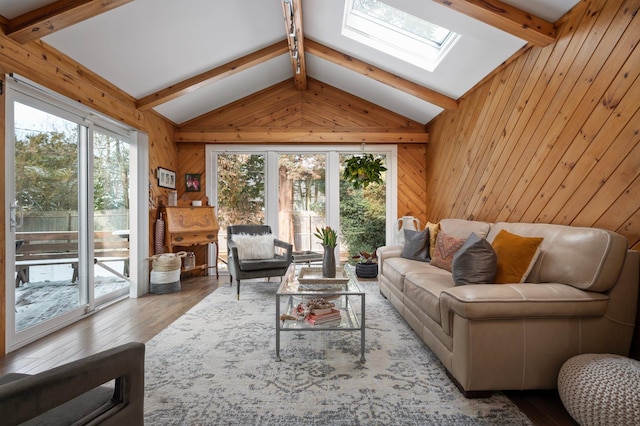 living room with lofted ceiling with skylight, wooden walls, and wood finished floors