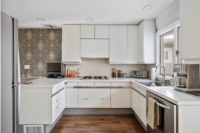 kitchen featuring a sink, stainless steel appliances, visible vents, and white cabinetry