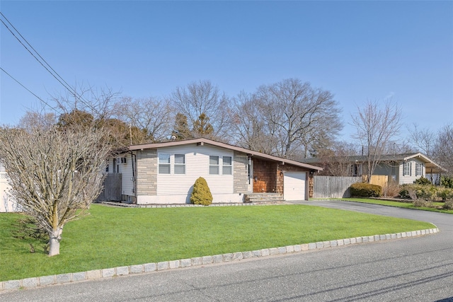 ranch-style house with a front yard, an attached garage, fence, and driveway