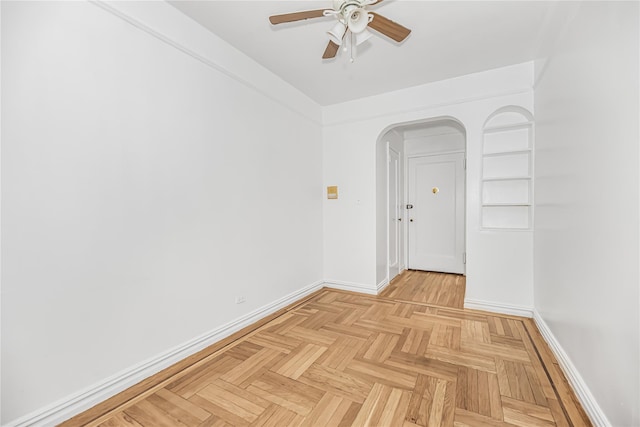 spare room featuring baseboards, arched walkways, and a ceiling fan