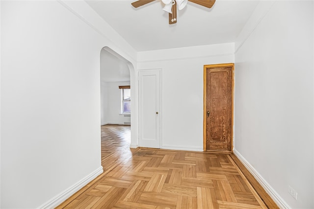 empty room with baseboards, arched walkways, and ceiling fan