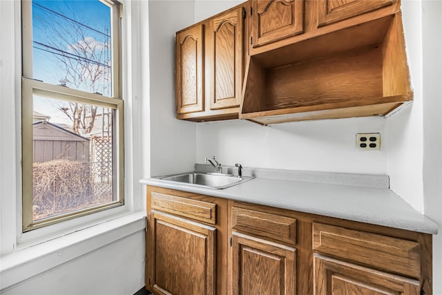 kitchen with a wealth of natural light, brown cabinetry, light countertops, and a sink