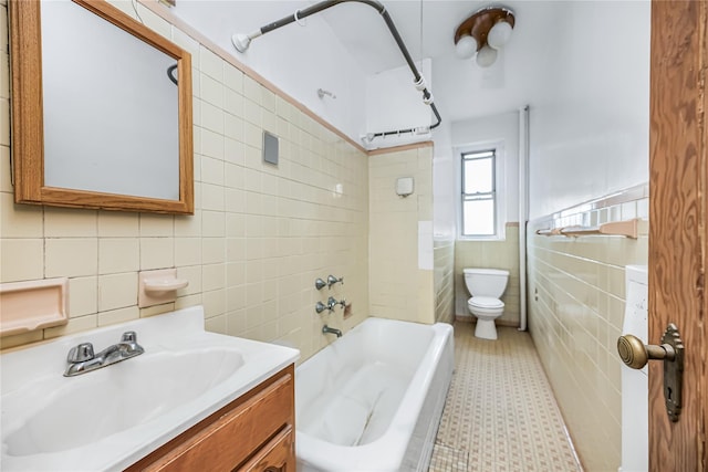 bathroom with vanity, tile walls, toilet, and shower / washtub combination