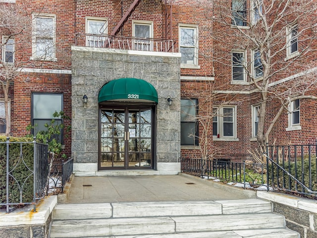 entrance to property with brick siding and a balcony