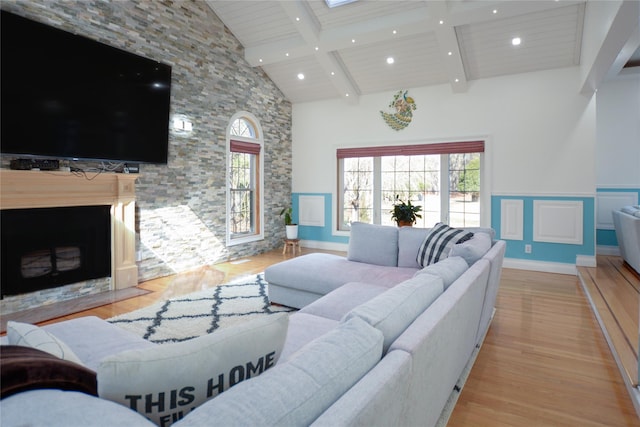 living area featuring beam ceiling, recessed lighting, a fireplace, wood finished floors, and high vaulted ceiling