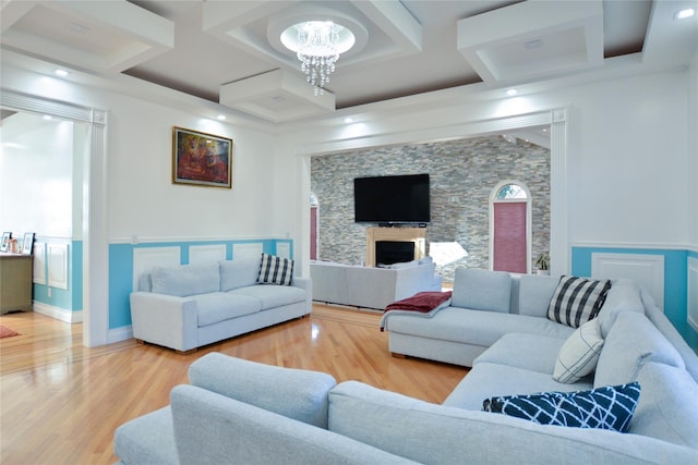 living room with wood finished floors, baseboards, coffered ceiling, a fireplace, and a chandelier