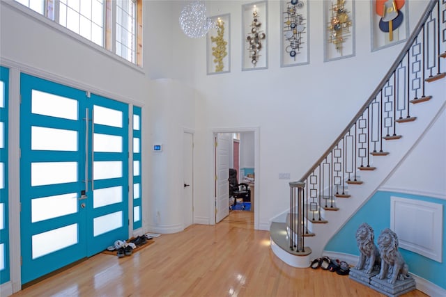 foyer entrance with stairway, wood finished floors, baseboards, french doors, and a towering ceiling