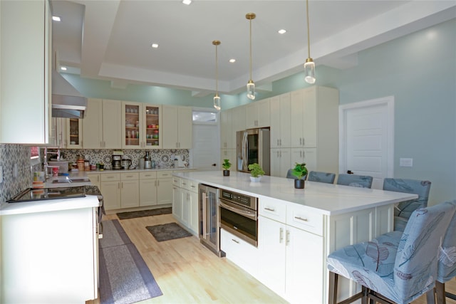 kitchen with a tray ceiling, decorative backsplash, wine cooler, glass insert cabinets, and appliances with stainless steel finishes