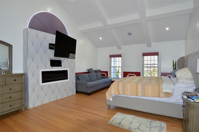 bedroom with lofted ceiling with beams, recessed lighting, wood finished floors, and a large fireplace