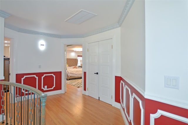 interior space with an upstairs landing, ornamental molding, and light wood finished floors