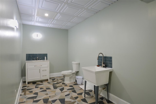 bathroom featuring toilet, baseboards, and a sink