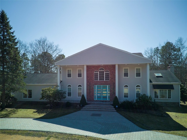 greek revival inspired property featuring a chimney and a front yard