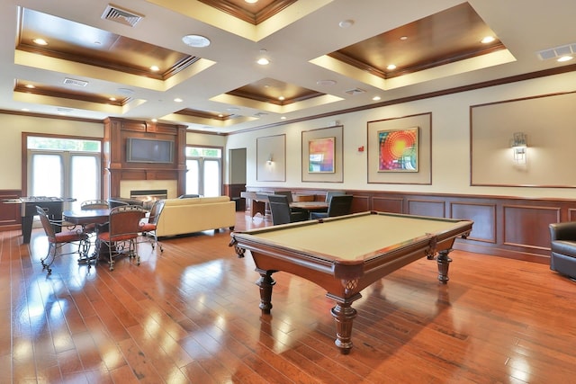 rec room featuring visible vents, hardwood / wood-style flooring, a glass covered fireplace, and a decorative wall