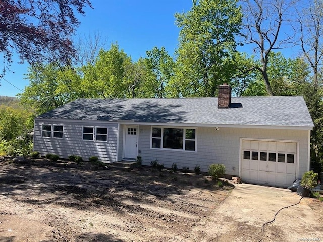 single story home featuring a shingled roof, a garage, driveway, and a chimney