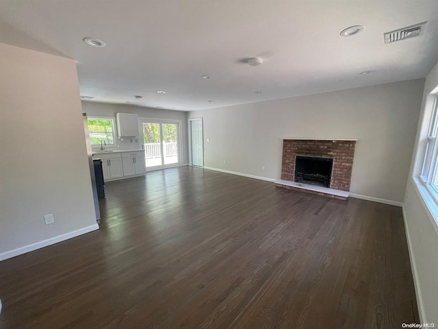 unfurnished living room featuring visible vents, baseboards, dark wood-type flooring, and a fireplace