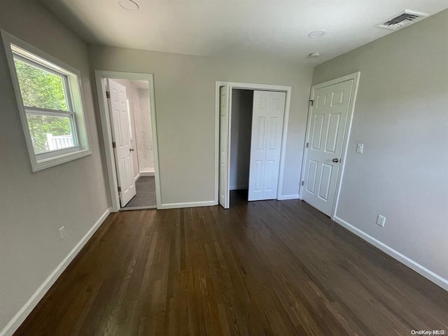 unfurnished bedroom featuring visible vents, baseboards, a closet, and dark wood-style flooring