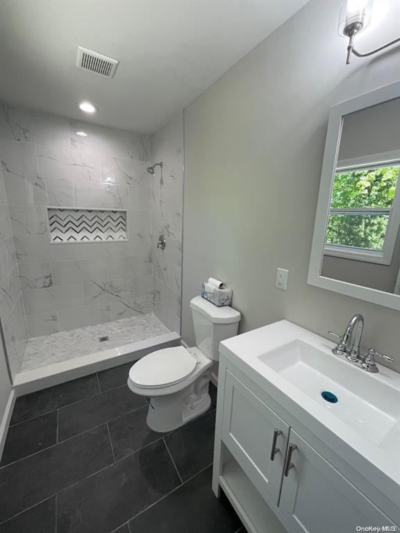 bathroom with vanity, visible vents, a stall shower, tile patterned flooring, and toilet