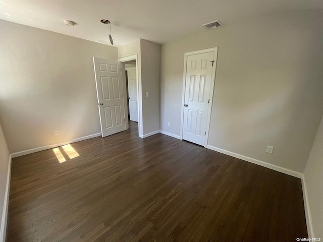 unfurnished room with visible vents, baseboards, and dark wood-style flooring