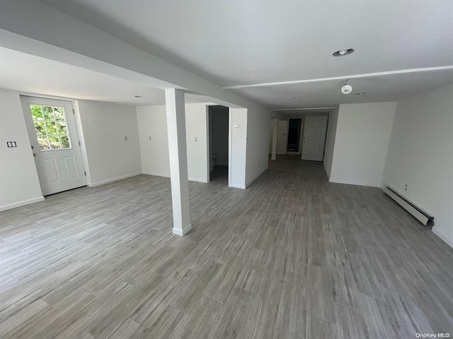 below grade area featuring a baseboard heating unit, wood finished floors, and baseboards