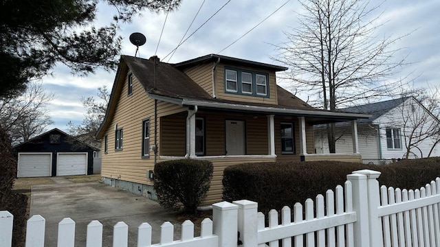 bungalow-style house with an outdoor structure, a porch, a detached garage, and a fenced front yard