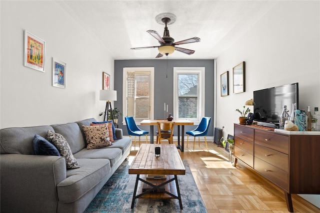 living area with baseboards and a ceiling fan