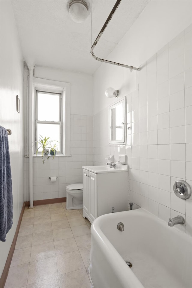 full bath with vanity, bathing tub / shower combination, tile patterned floors, toilet, and tile walls