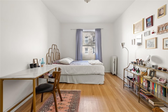 bedroom with light wood-style flooring, radiator heating unit, and baseboards