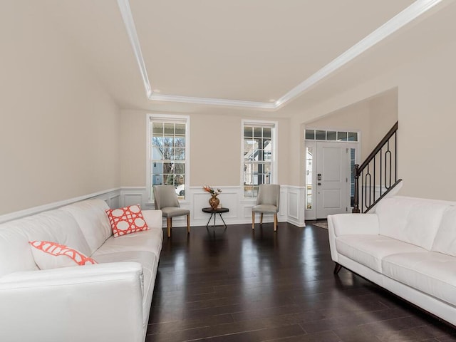 living room featuring crown molding, a wainscoted wall, wood finished floors, a decorative wall, and a raised ceiling