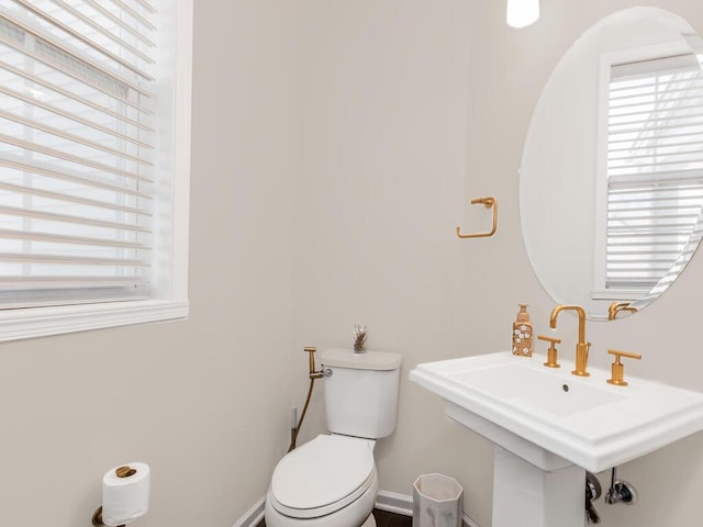 bathroom featuring baseboards, plenty of natural light, and toilet