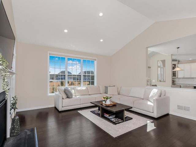 living area featuring dark wood finished floors, visible vents, a fireplace, and vaulted ceiling