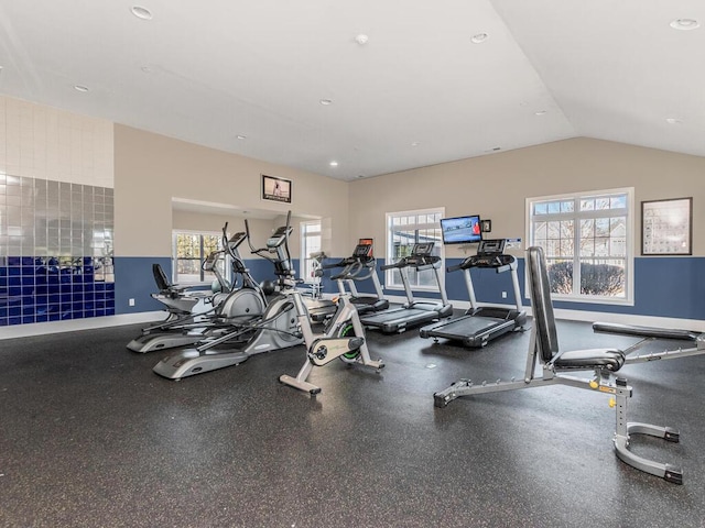 exercise room with baseboards, plenty of natural light, and vaulted ceiling