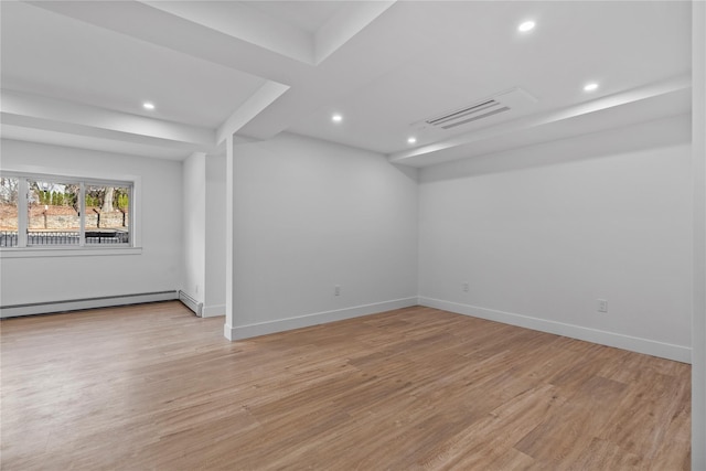 unfurnished room featuring visible vents, light wood-style flooring, a baseboard heating unit, and baseboards