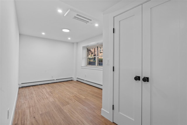 empty room with recessed lighting, a baseboard radiator, visible vents, and wood finished floors