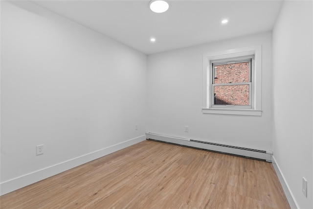 empty room featuring a baseboard heating unit, recessed lighting, baseboards, and light wood finished floors