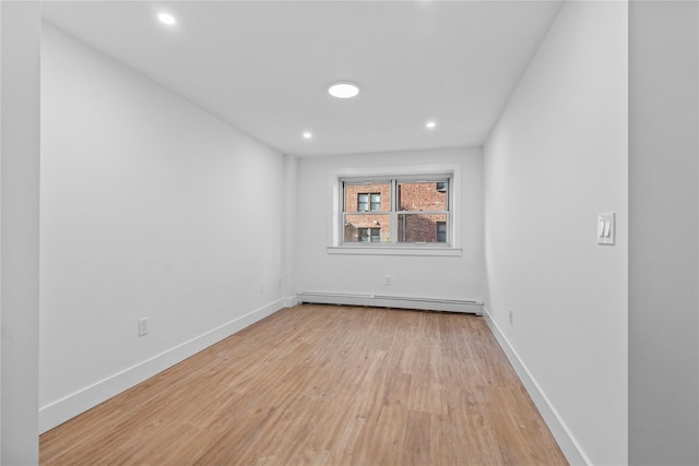 empty room featuring recessed lighting, baseboard heating, light wood-style flooring, and baseboards