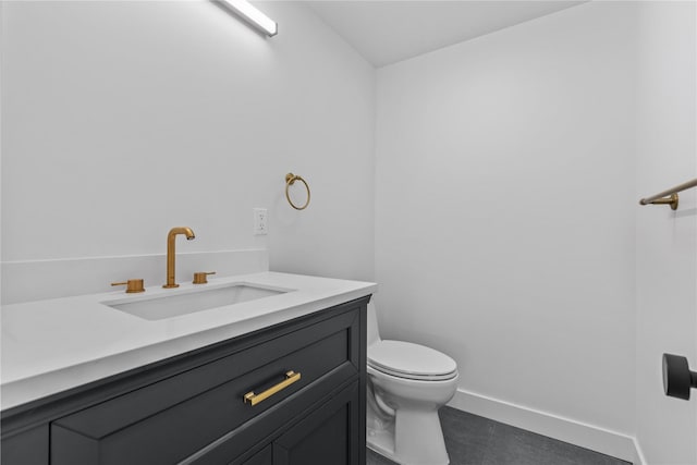 bathroom with toilet, vanity, and baseboards