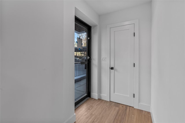 corridor featuring light wood-type flooring and baseboards